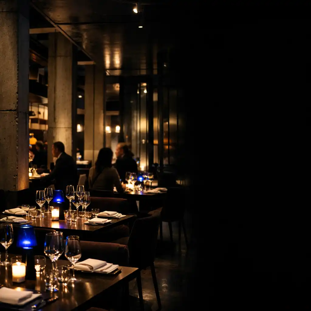 Dunkler Restaurantinnenraum mit gedeckten Tischen, Beton, Stahl und Abendlicht